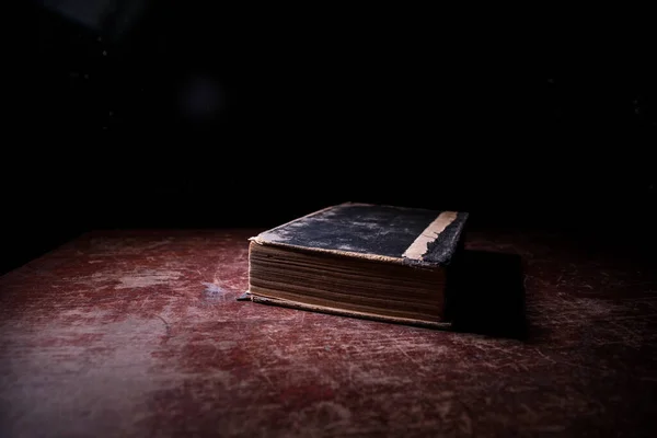 一堆旧书 木制桌子上的旧书 黑暗的房间里 一个发光的书周围闪烁着神奇的闪电 有选择的重点 — 图库照片