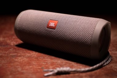 BAKU. AZERBAIJAN - 28.07.2020: JBL Flip 4 Bluetooth Hoparlörü, ahşap masaya yakın çekim, renkli ışıklar ve arka planda sis. Seçici odak