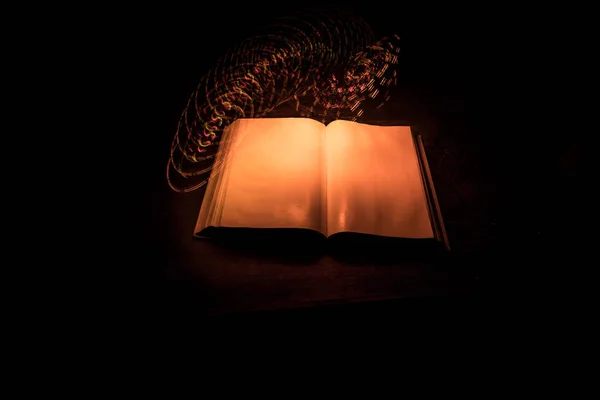 一堆旧书 木制桌子上的旧书 黑暗的房间里 一个发光的书周围闪烁着神奇的闪电 有选择的重点 — 图库照片