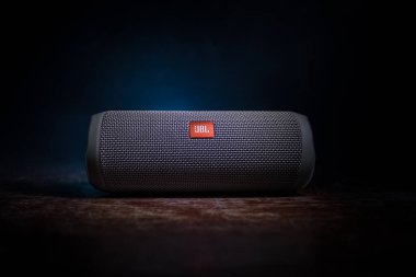 BAKU. AZERBAIJAN - 28.07.2020: JBL Flip 4 Bluetooth Hoparlörü, ahşap masaya yakın çekim, renkli ışıklar ve arka planda sis. Seçici odak