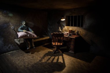 Hapisteki adam demir parmaklıklar arkasında. Eski edepsiz hapishane minyatürü. Karanlık hapishane iç dekorasyonu. İçinde minyatür bir masa var. Seçici odak