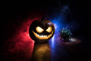 Corona virüsü küresel pandemik konsepti sırasında Cadılar Bayramı. Karanlıkta parlayan balkabakları ve Covid romanı tematik ürkütücü süslemelerle. Cadılar Bayramı balkabağı sisli arka planda. Seçici odak