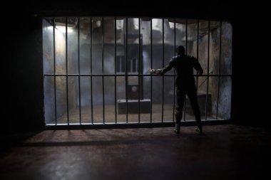 Uygulama kavramı. Eski hapishanede idam cezası giyotini minyatürü. Eski hapishane parmaklıkları hücre kilidi. Hapisteki adam. Karanlıkta Giyotin ölçeği modelinin korkunç görünümü