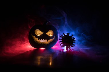 Corona virüsü küresel pandemik konsepti sırasında Cadılar Bayramı. Karanlıkta parlayan balkabakları ve Covid romanı tematik ürkütücü süslemelerle. Cadılar Bayramı balkabağı sisli arka planda. Seçici odak