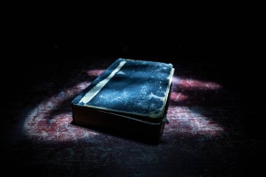 Bir yığın eski kitap. Ahşap masanın üzerinde antika bir kitap. Karanlıkta parlayan bir kitabın etrafında sihirli bir yıldırım. Seçici odak