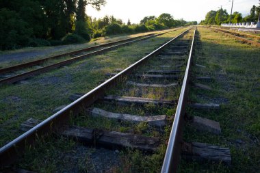 Gün batımında güzel gökyüzüne karşı tren istasyonu. Demiryolu, bulutlu, güneşli, ağaçlı ve yeşil çimenli sanayi manzarası. Azerbaycan doğası