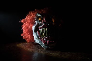 Tahta masadaki Ürkütücü Palyaço kafası. Karanlık sisli arka planda gülümseyen şeytani palyaço. Cadılar Bayramı konsepti Seçici odak