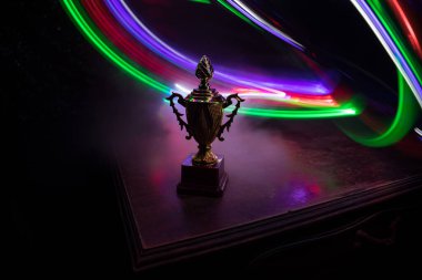 Altın kupa masa arkasında fotokopi alanı olan bir kupa. Renkli sisli arka ışıklandırmalı yaratıcı sanat dekorasyonu. Seçici odak