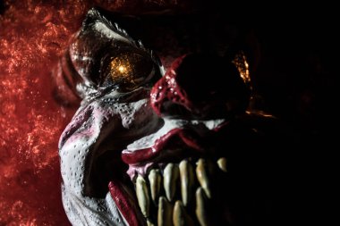 Tahta masadaki Ürkütücü Palyaço kafası. Karanlık sisli arka planda gülümseyen şeytani palyaço. Cadılar Bayramı konsepti Seçici odak