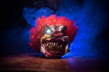 Tahta masadaki Ürkütücü Palyaço kafası. Karanlık sisli arka planda gülümseyen şeytani palyaço. Cadılar Bayramı konsepti Seçici odak