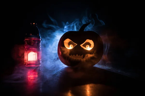 Halloween pumpkin smile and scary eyes for party night. Close up view of scary Halloween pumpkin with eyes glowing inside at black background. Selective focus