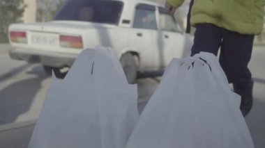 Çocuğun plastik poşetleri taşımaya çalışırken çekilmiş yakın çekim görüntüleri.
