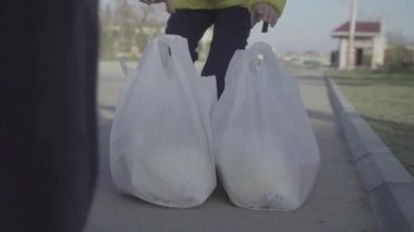 Çocuğun plastik poşetleri taşımaya çalışırken çekilmiş yakın çekim görüntüleri.