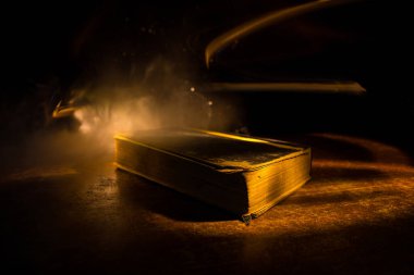 Bir yığın eski kitap. Ahşap masanın üzerinde antika bir kitap. Karanlıkta parlayan bir kitabın etrafında sihirli bir yıldırım. Seçici odak