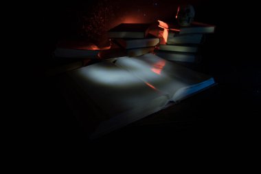 Bir yığın eski kitap. Ahşap masanın üzerinde antika bir kitap. Karanlıkta parlayan bir kitabın etrafında sihirli bir yıldırım. Seçici odak