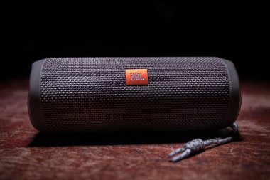 BAKU. AZERBAIJAN - 28.07.2020: JBL Flip 4 Bluetooth Hoparlörü, ahşap masaya yakın çekim, renkli ışıklar ve arka planda sis. Seçici odak