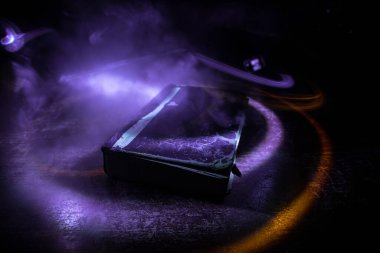 Bir yığın eski kitap. Ahşap masanın üzerinde antika bir kitap. Karanlıkta parlayan bir kitabın etrafında sihirli bir yıldırım. Seçici odak