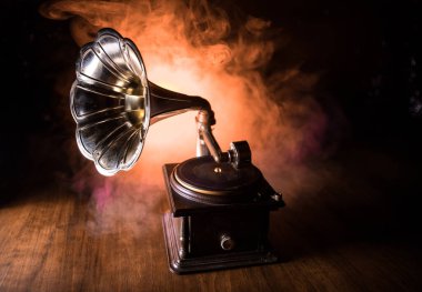 Music concept. Old gramophone on a dark background. Retro gramophone with disc on wooden table with toned backlight. Selective focus clipart