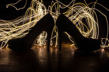 Sanat dekorasyonu. Karanlıkta topuklu kadın ayakkabılarının silueti. Kadın gücü ya da kadın egemenliği kavramı. Seçici odak
