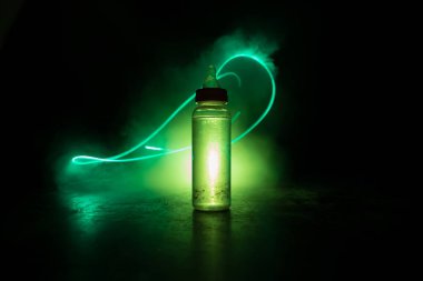 Bebek şişesini ahşap masadaki koyu tonlu sisli arka planda, ışıkla kapatın. Yaratıcı sanat eserleri dekore edilmiş fotoğraf. Seçici odak.