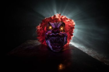 Tahta masadaki Ürkütücü Palyaço kafası. Karanlık sisli arka planda gülümseyen şeytani palyaço. Cadılar Bayramı konsepti Seçici odak