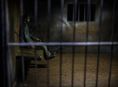 Hapisteki adam demir parmaklıklar arkasında. Eski edepsiz hapishane minyatürü. Karanlık hapishane iç dekorasyonu. Seçici odak