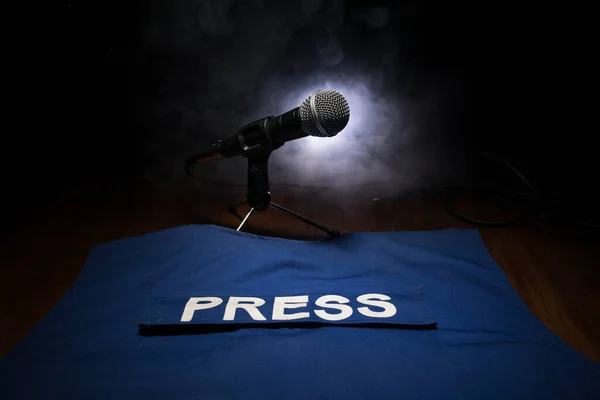 Media Journalism Global Daily News Content Concept. Blue journalist (press) vest in dark with backlight and fog. Media microphone on journalist vest. Selective focus