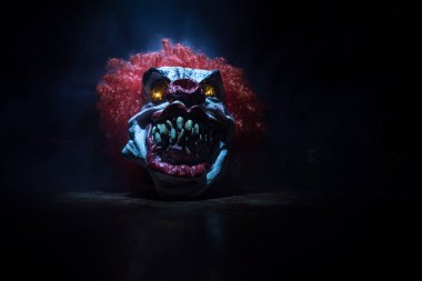 Tahta masadaki Ürkütücü Palyaço kafası. Karanlık sisli arka planda gülümseyen şeytani palyaço. Cadılar Bayramı konsepti Seçici odak