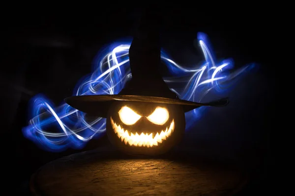 Halloween pumpkin smile and scary eyes for party night. Close up view of scary Halloween pumpkin with eyes glowing inside at black background. Selective focus