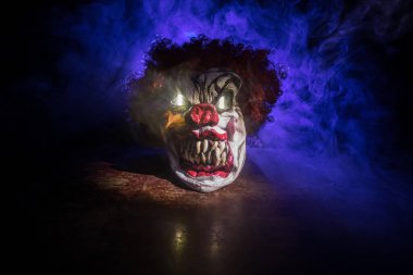Tahta masadaki Ürkütücü Palyaço kafası. Karanlık sisli arka planda gülümseyen şeytani palyaço. Cadılar Bayramı konsepti Seçici odak