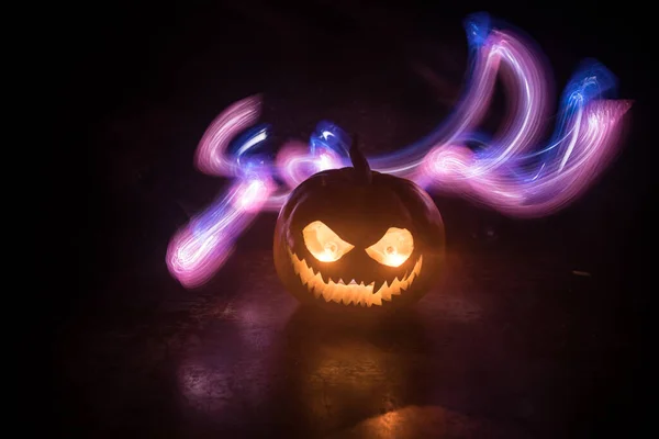 Halloween pumpkin smile and scary eyes for party night. Close up view of scary Halloween pumpkin with eyes glowing inside at black background. Selective focus