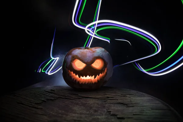 Halloween pumpkin smile and scary eyes for party night. Close up view of scary Halloween pumpkin with eyes glowing inside at black background. Selective focus