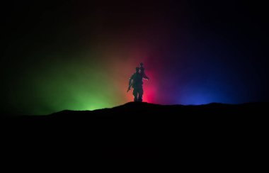 Azeri ordusu konsepti. Azerbaycan bayrağına karşı silahlı askerlerin silueti. Azeri askeri omzunda küçük bir çocuk taşıyor. Yaratıcı sanat dekorasyonu. Askeri siluetler dövüş sahnesinde sisli bir arka planda. Seçici odak