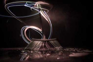 Karanlık bir zemin üzerinde, ışık ve sis ile yakın plan fırçala. Karanlıkta süpürge. Temizlik konsepti. Seçici odak