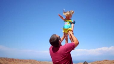 Baba çocuk onun kollarında yükseltir.