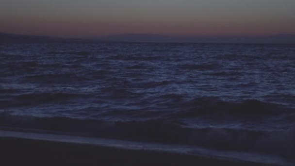 Спокойное море ночью с горами на заднем плане — стоковое видео