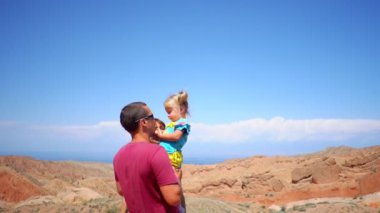 Baba çocuk onun kollarında yükseltir.