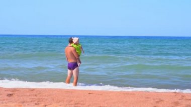 Babası deniz kenarında bir çocuk gibi duruyor.