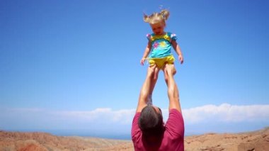 Baba çocuk onun kollarında yükseltir.