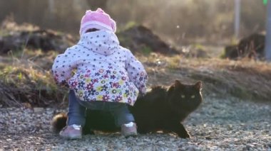 sokakta bir kedi ile oynayan bir çocuk