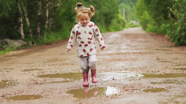 Het kind loopt door plassen in rubberen laarzen — Stockvideo