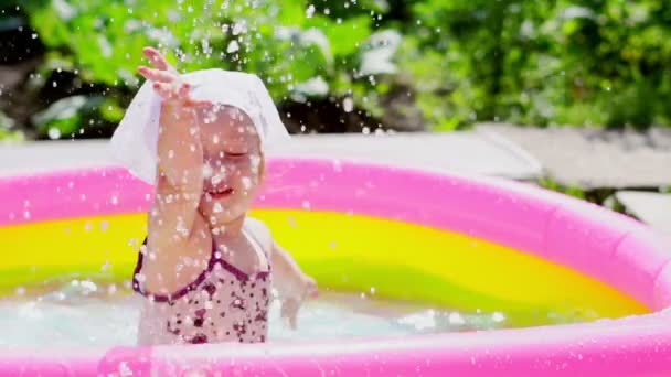 Uma criança nada em uma piscina inflável — Vídeo de Stock