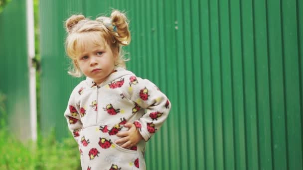フェンスの近くの村に立っている小さな女の子 — ストック動画