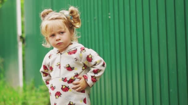 Une petite fille debout dans le village près de la clôture — Video