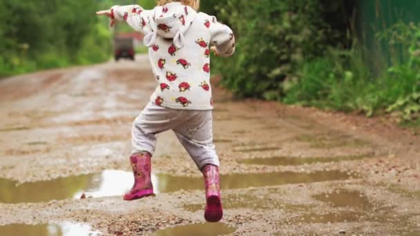 El niño corre a través de charcos en botas de goma — Vídeos de Stock