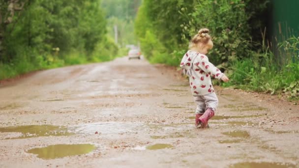 子供はゴムブーツの水たまりを通り抜ける — ストック動画