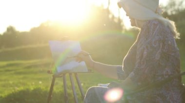 yaşlı bir kadın doğada çizer