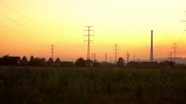evlerin yakınında gün batımında yüksek gerilim kuleleri