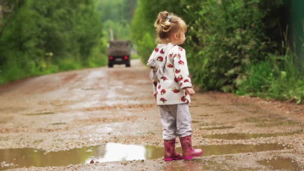 The child runs through puddles in rubber boots — Stock Video