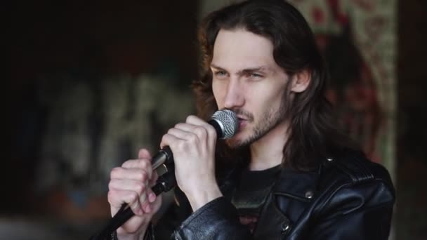Een zanger zingt in een microfoon in een oud gebouw — Stockvideo